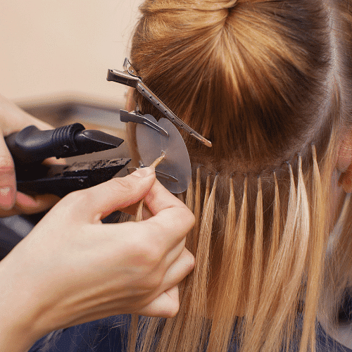A stylist applying hair dye to a client's hair with foil.